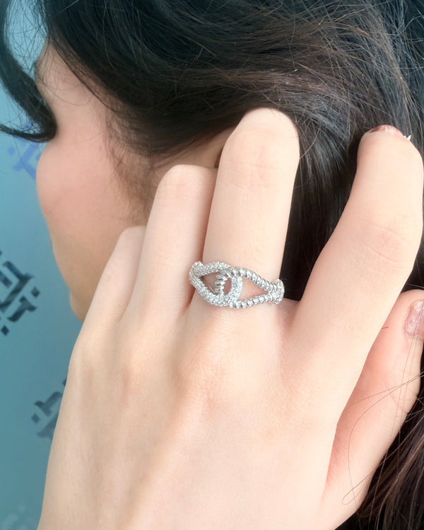 Close-up of a hand wearing a silver ring with a blue background