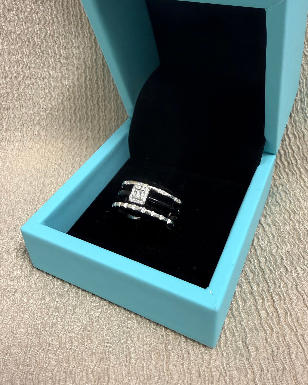 Blue jewelry box with a ring on a beige surface