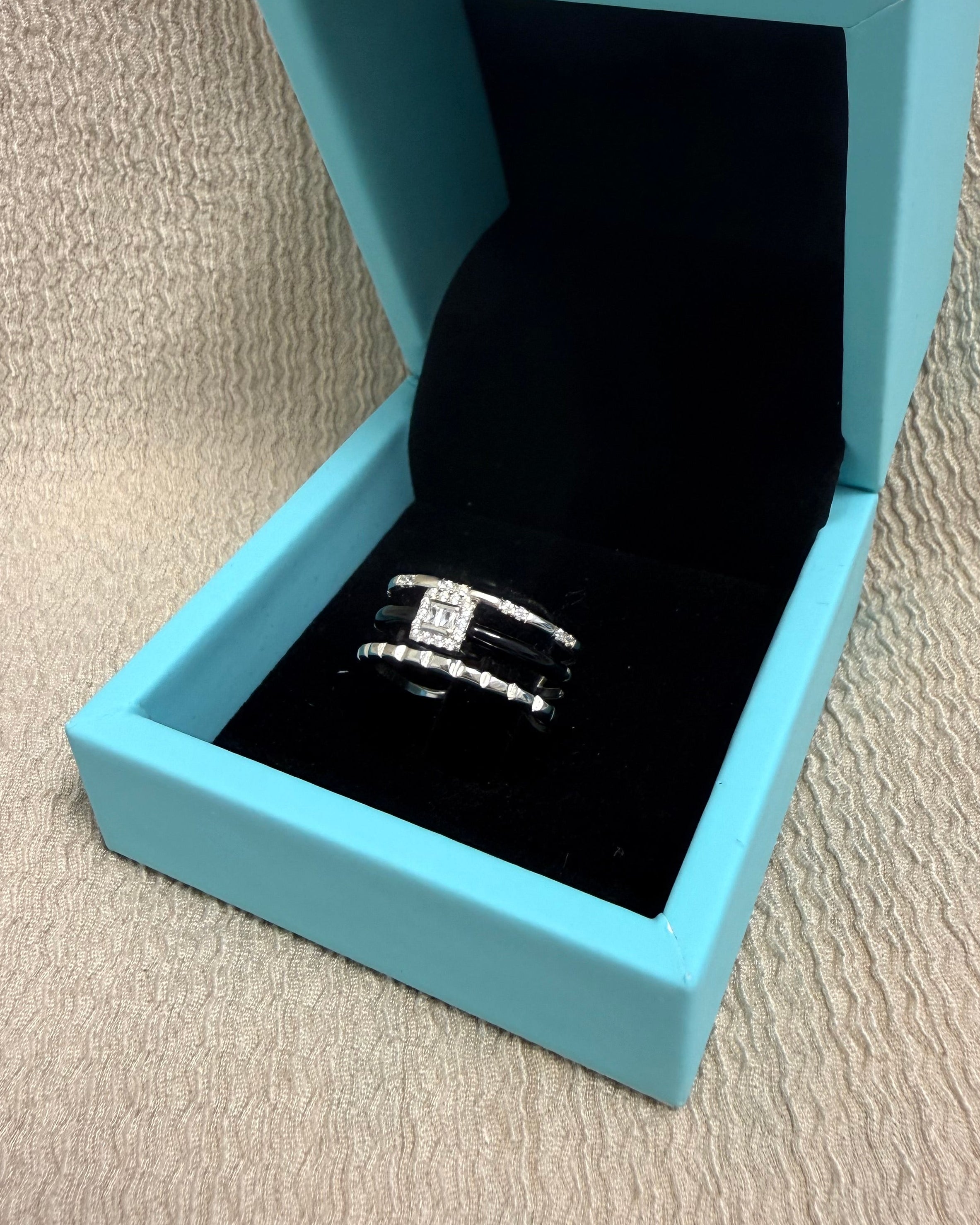 Blue jewelry box with a ring on a beige surface