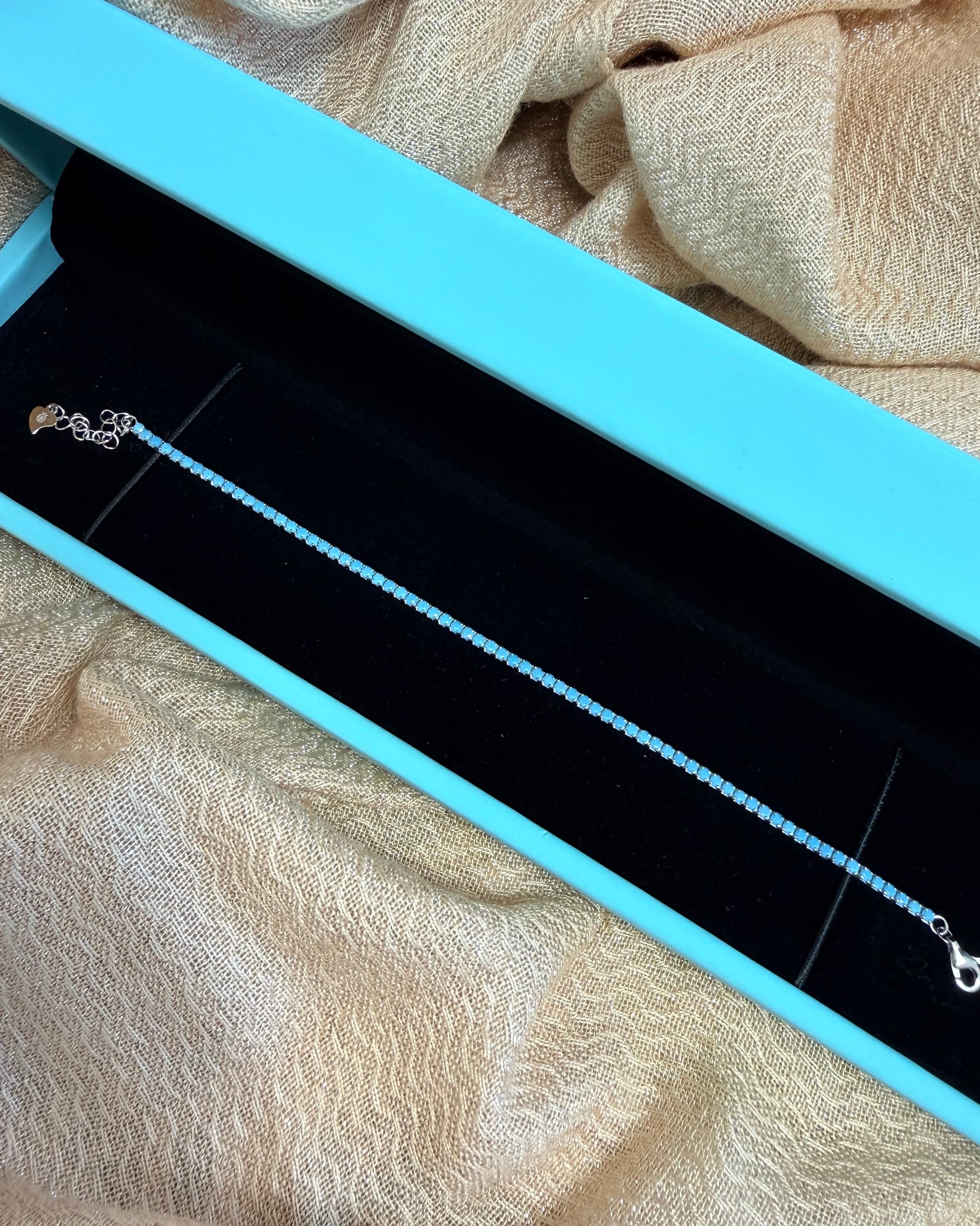 Necklace in a blue jewelry box on a textured beige fabric background